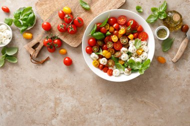 Taze kiraz domatesli salata, mozzarella ve fesleğen yaprakları, üst manzara.