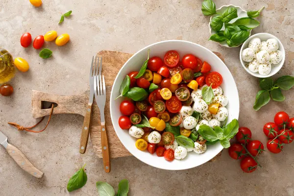 Taze kiraz domatesli salata, mozzarella ve fesleğen yaprakları, üst manzara.