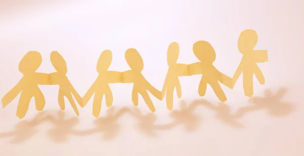 Team of paper chain people united together holding hands