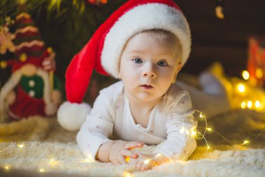 Güzel küçük bebek Noel ağacının altında yerde yatıyor Noel hediyeleri ve ışıklarla