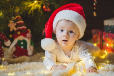 Güzel küçük bebek Noel ağacının altında yerde yatıyor Noel hediyeleri ve ışıklarla