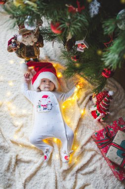 Güzel küçük bebek Noel ağacının altında yerde yatıyor Noel hediyeleri ve ışıklarla