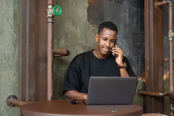 Portrait of handsome black man sitting and using laptop computer indoors