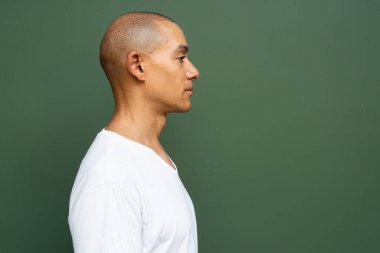 Portrait of handsome bald man wearing t-shirt against plain background