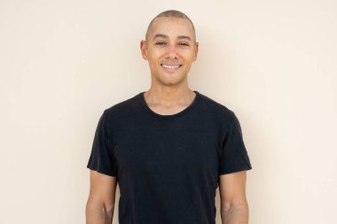 Portrait of handsome bald man wearing t-shirt against plain background