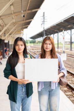Tren istasyonunda iki genç Asyalı kadının portresi.