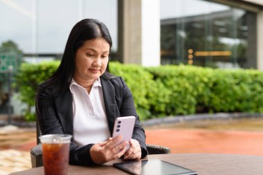 Restoranda oturmuş buzlu kahve içen Asyalı bir kadın.