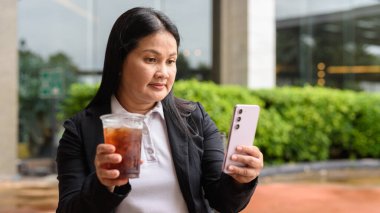 Restoranda oturmuş buzlu kahve içen Asyalı bir kadın.