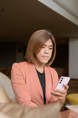 Kendine güvenen Asyalı transseksüel. İkili olmayan kişi şık bir kapalı kafe restoranında iş kıyafeti giyiyor.