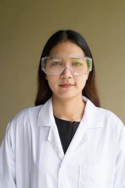 Laboratuvar önlüğü ve gözlüğü takan genç Asyalı bilim kadını.