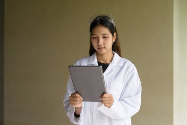 Laboratuvar önlüğü ve gözlüğü takan genç Asyalı bilim kadını.