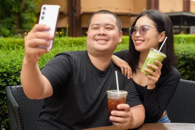 Mutlu Asyalı çift yaz boyunca açık hava kafe restoranında birlikte oturuyorlar.