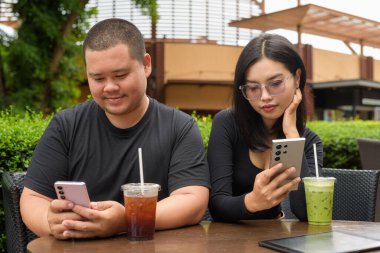 Mutlu Asyalı çift yaz boyunca açık hava kafe restoranında birlikte oturuyorlar.