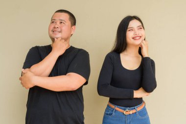 Duvarın arkasında duran Asyalı genç bir çiftin portresi.