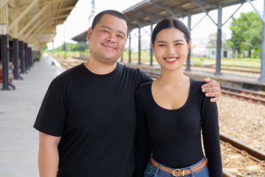 Genç Asyalı çift tren istasyonunda beraberler.