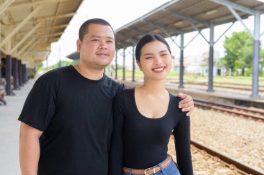 Genç Asyalı çift tren istasyonunda beraberler.