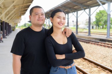 Genç Asyalı çift tren istasyonunda beraberler.