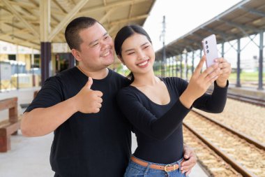 Genç Asyalı çift tren istasyonunda beraberler.