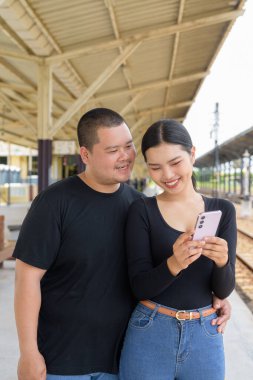 Genç Asyalı çift tren istasyonunda beraberler.