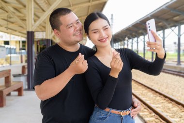 Genç Asyalı çift tren istasyonunda beraberler.