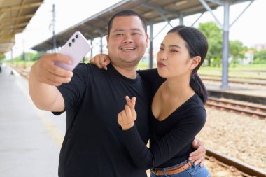 Genç Asyalı çift tren istasyonunda beraberler.