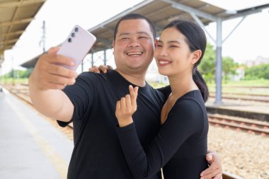 Genç Asyalı çift tren istasyonunda beraberler.