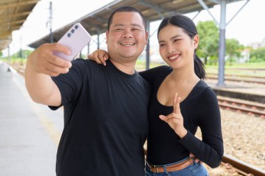 Genç Asyalı çift tren istasyonunda beraberler.