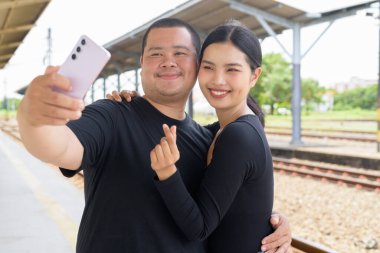 Genç Asyalı çift tren istasyonunda beraberler.