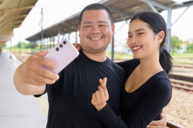 Genç Asyalı çift tren istasyonunda beraberler.