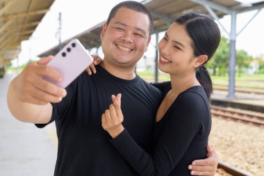 Genç Asyalı çift tren istasyonunda beraberler.