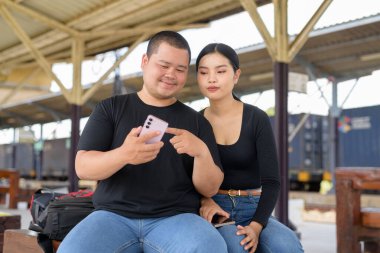 Genç Asyalı çift tren istasyonunda beraberler.