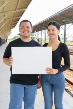 Genç Asyalı çift tren istasyonunda beraberler.