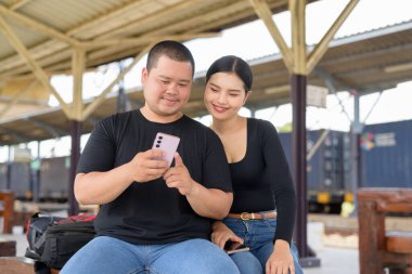 Genç Asyalı çift tren istasyonunda beraberler.