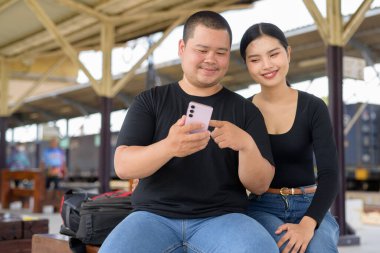 Genç Asyalı çift tren istasyonunda beraberler.