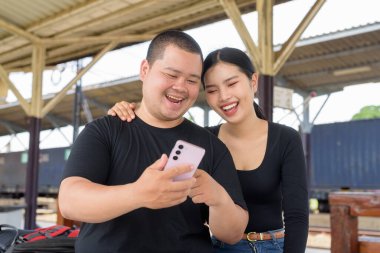 Genç Asyalı çift tren istasyonunda beraberler.