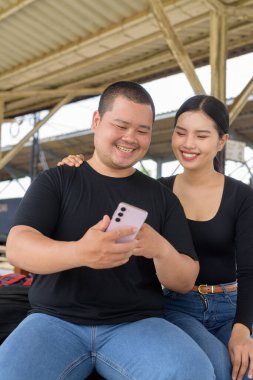 Genç Asyalı çift tren istasyonunda beraberler.