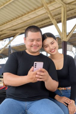 Genç Asyalı çift tren istasyonunda beraberler.