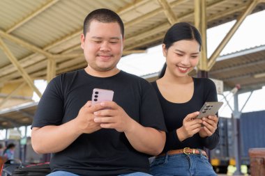 Genç Asyalı çift tren istasyonunda beraberler.