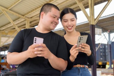 Genç Asyalı çift tren istasyonunda beraberler.