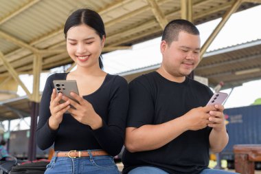 Genç Asyalı çift tren istasyonunda beraberler.