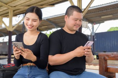 Genç Asyalı çift tren istasyonunda beraberler.