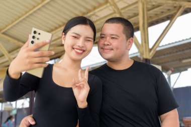 Genç Asyalı çift tren istasyonunda beraberler.