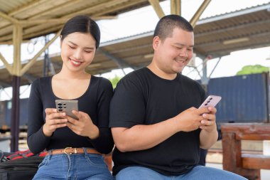 Genç Asyalı çift tren istasyonunda beraberler.