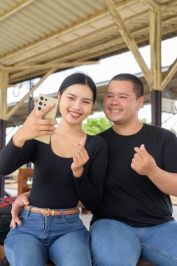 Genç Asyalı çift tren istasyonunda beraberler.