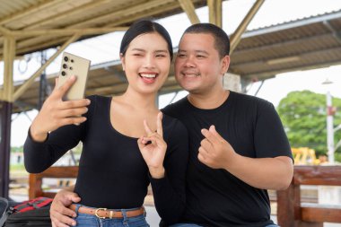 Genç Asyalı çift tren istasyonunda beraberler.