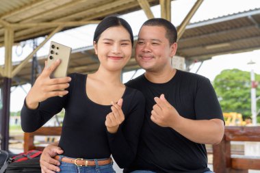 Genç Asyalı çift tren istasyonunda beraberler.