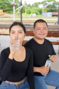 Genç Asyalı çift tren istasyonunda beraberler.