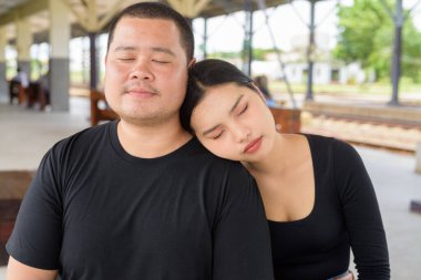 Genç Asyalı çift tren istasyonunda beraberler.