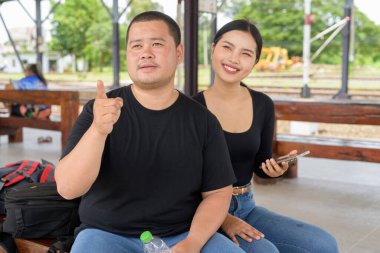 Genç Asyalı çift tren istasyonunda beraberler.