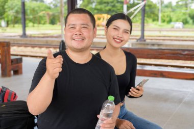 Genç Asyalı çift tren istasyonunda beraberler.